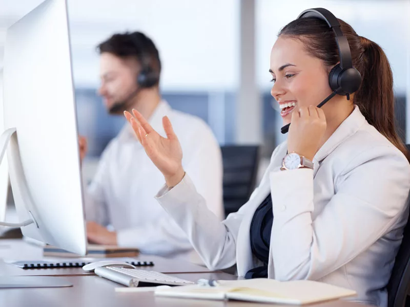 Outsourced IT help desk agent wearing a headset taking a support call at a monitored workstation